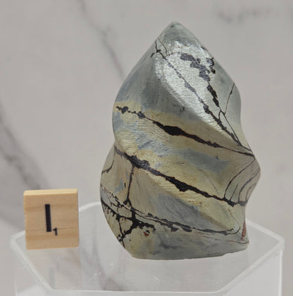Picture Jasper carving resembling a flame on a clear stand against a neutral background