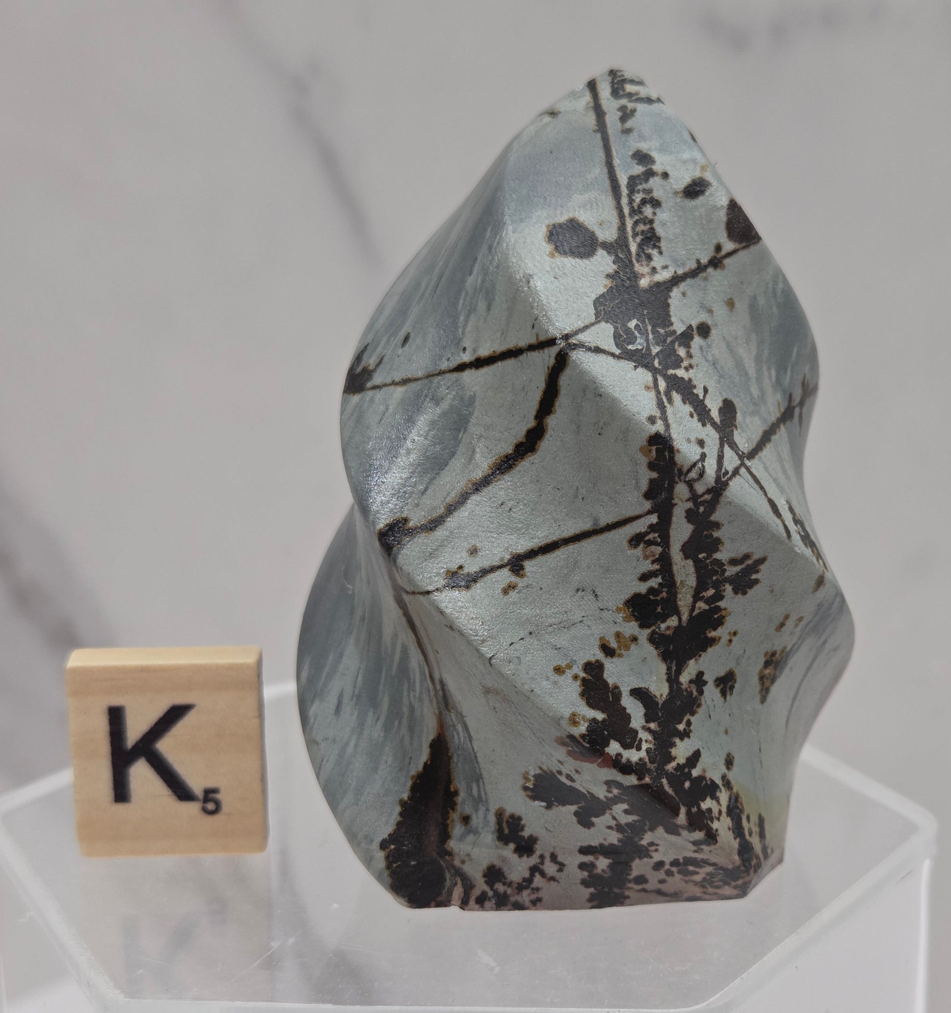 Picture Jasper carving resembling a flame on a clear stand against a neutral background