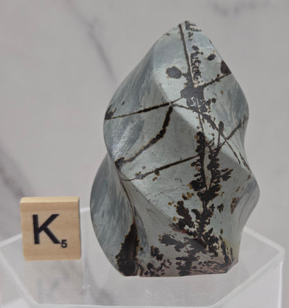 Picture Jasper carving resembling a flame on a clear stand against a neutral background
