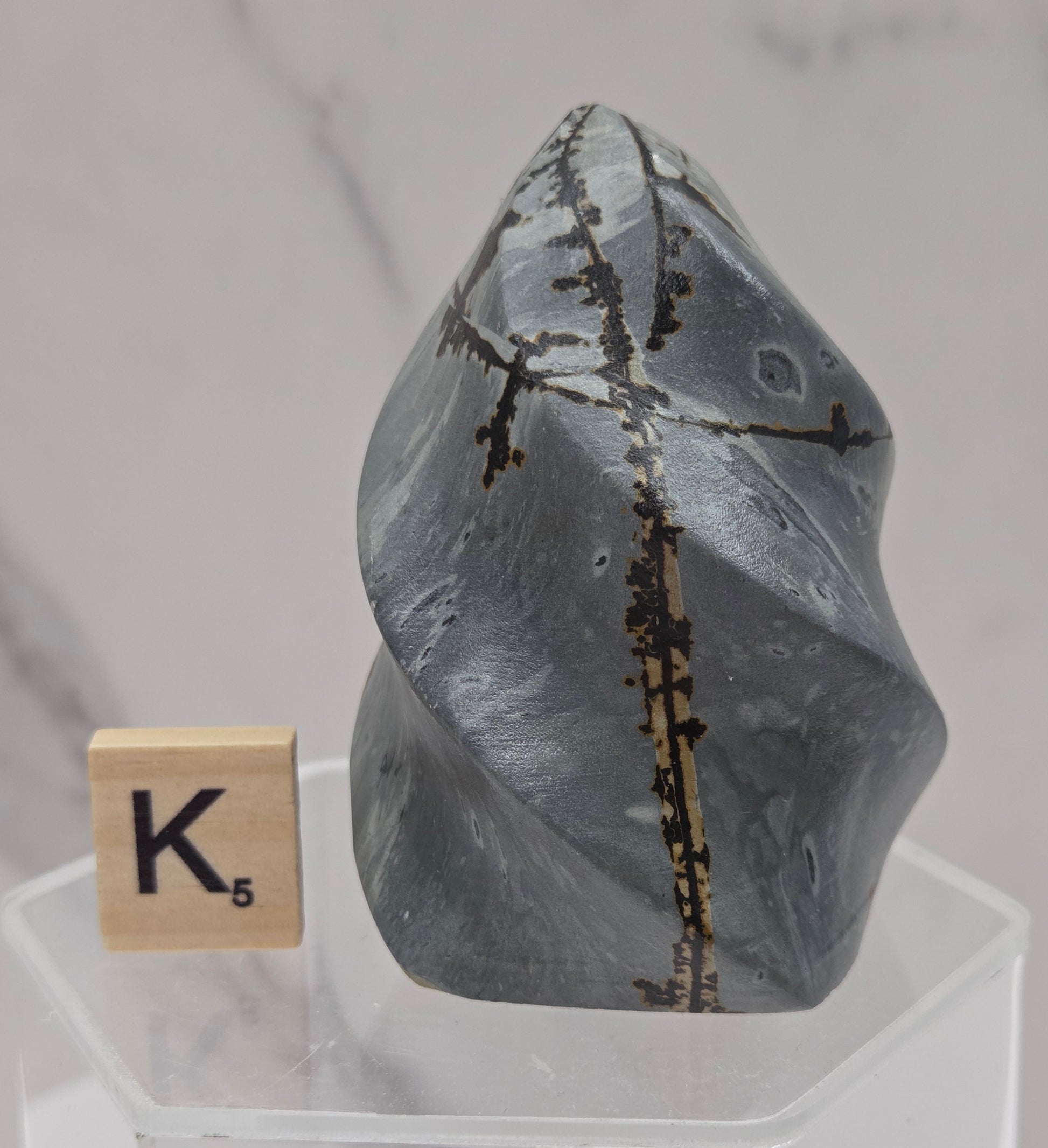 Picture Jasper carving resembling a flame on a clear stand against a neutral background
