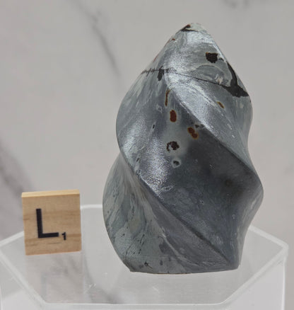 Picture Jasper carving resembling a flame on a clear stand against a neutral background