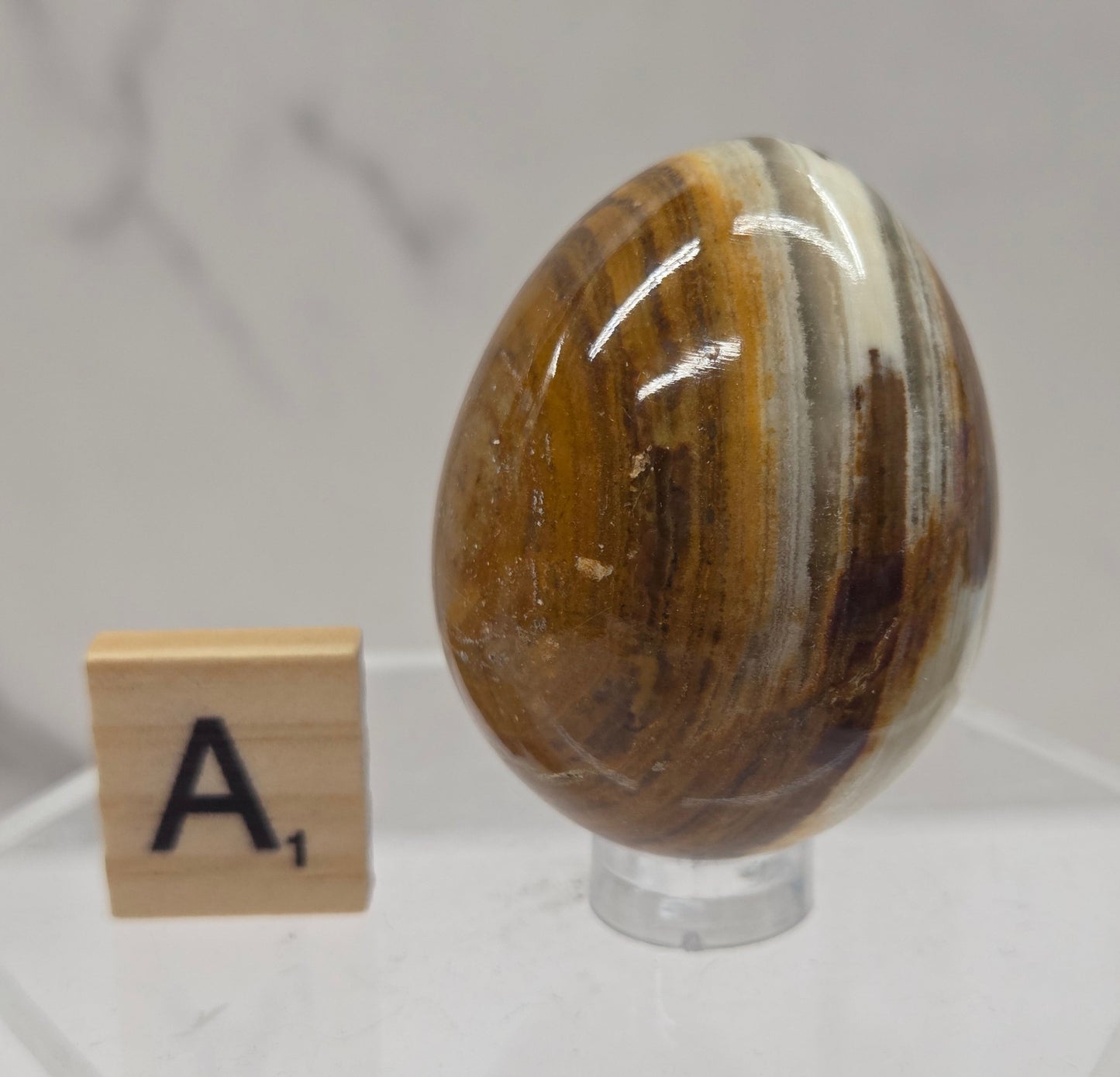 Afghan jade egg carving with green and brown bands against a neutral background