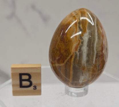 Afghan jade egg carving with green and brown bands against a neutral background