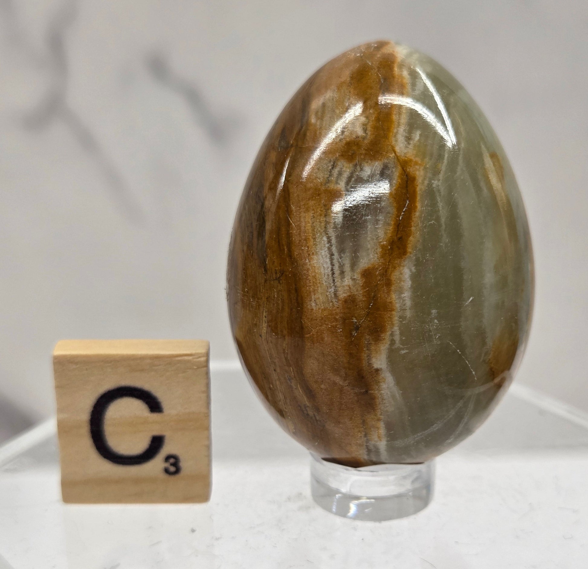 Afghan jade egg carving with green and brown bands against a neutral background