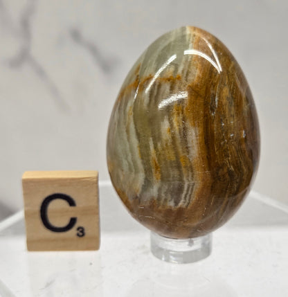 Afghan jade egg carving with green and brown bands against a neutral background