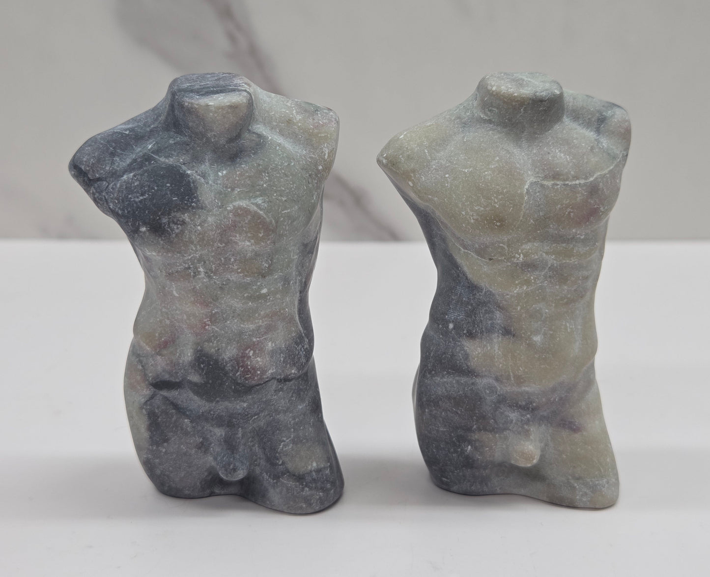 Two jasper male torso carvings against a white background