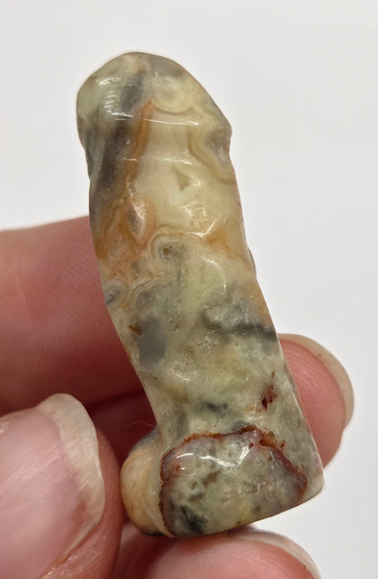 Hand holding a male anatomy crystal carving on a white background