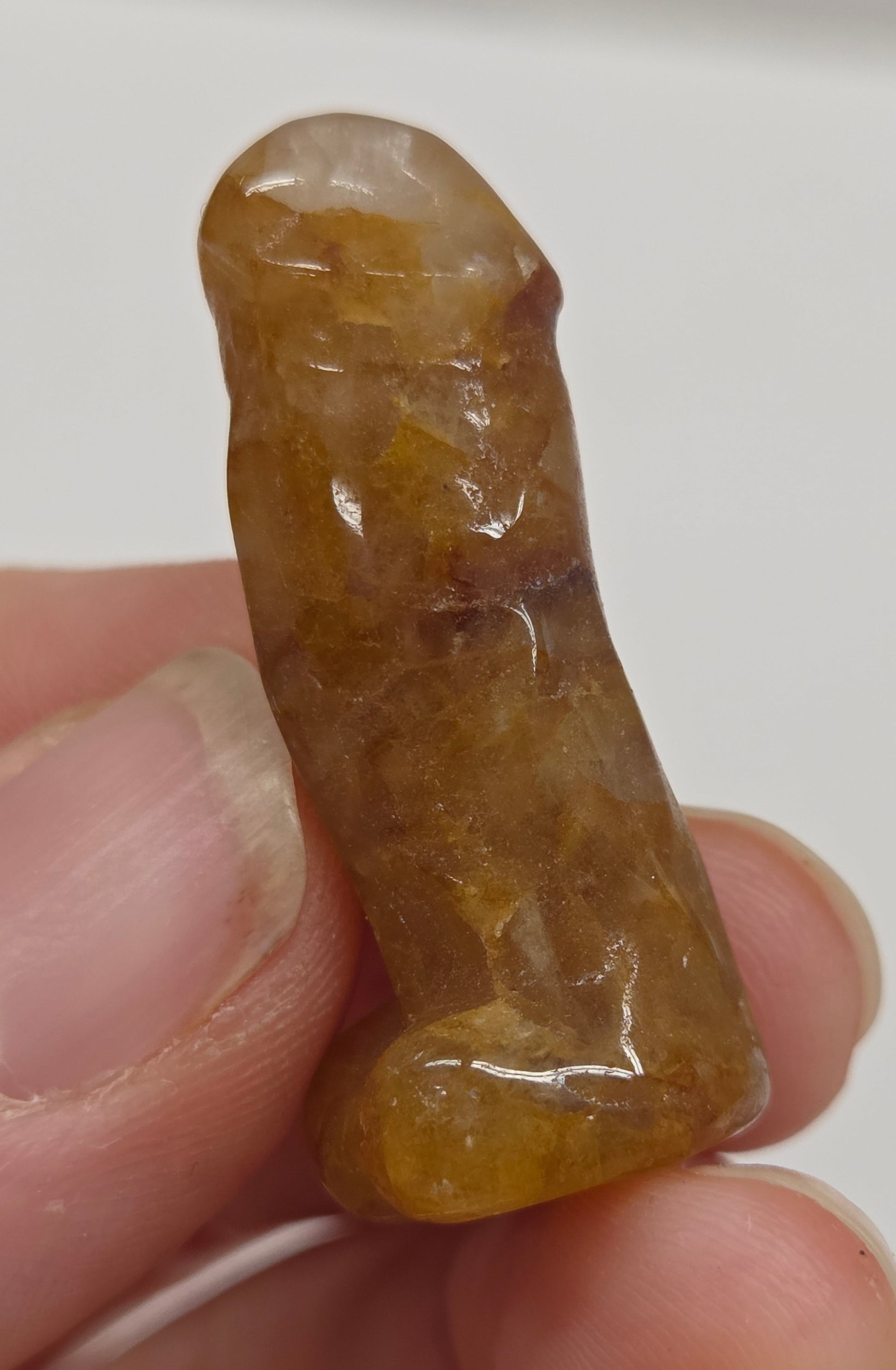 Hand holding a male anatomy crystal carving on a white background