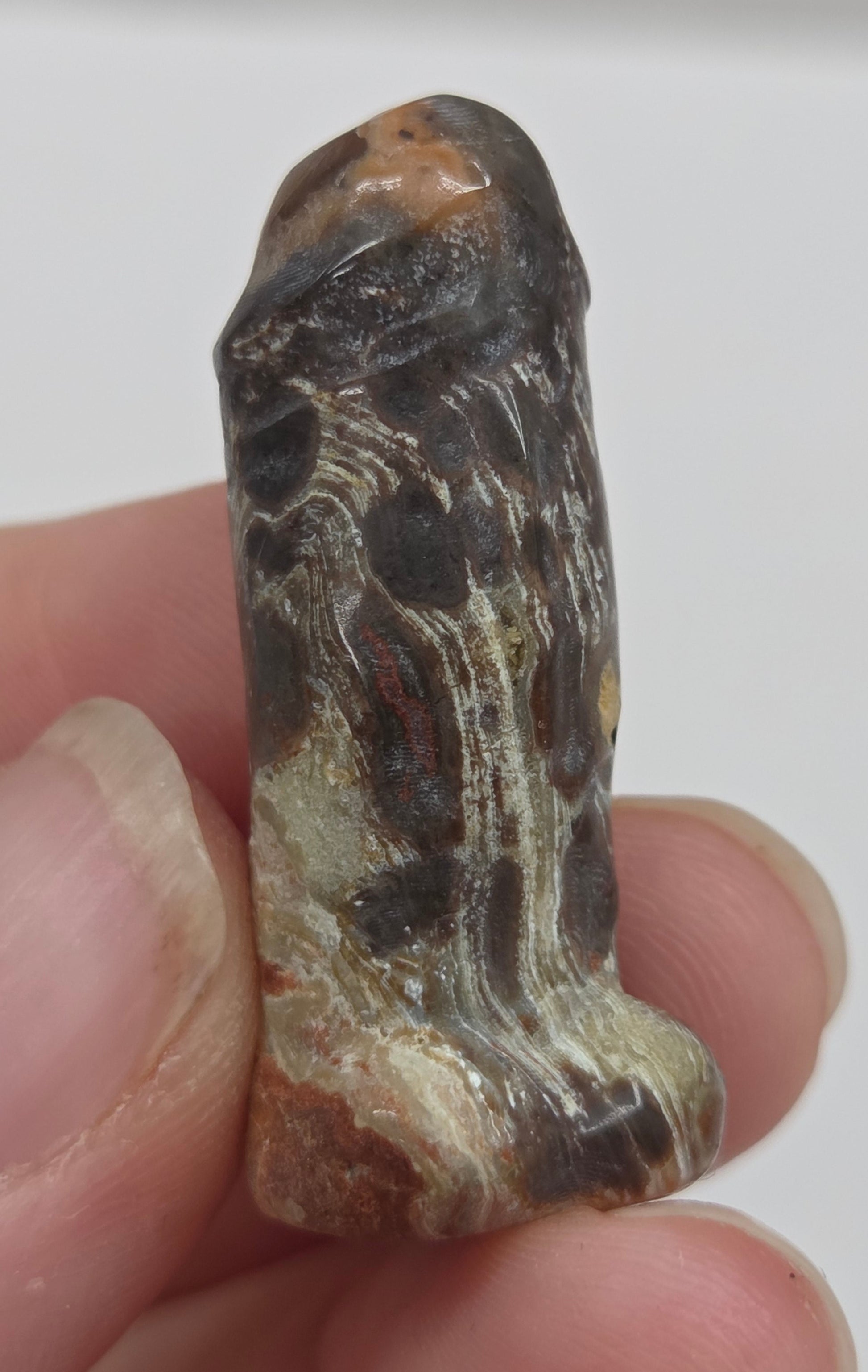 Hand holding a male anatomy crystal carving on a white background