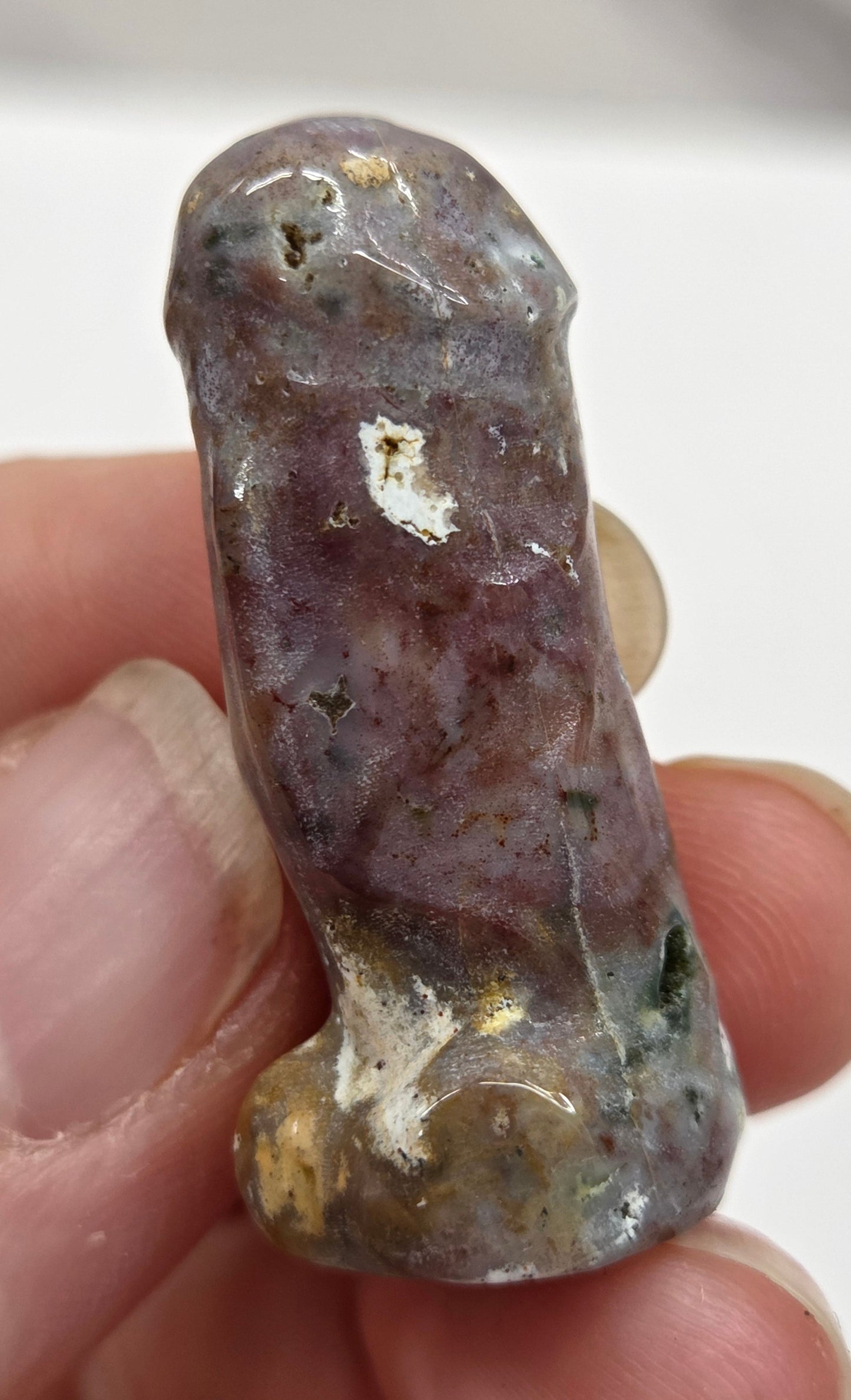 Hand holding a male anatomy crystal carving on a white background