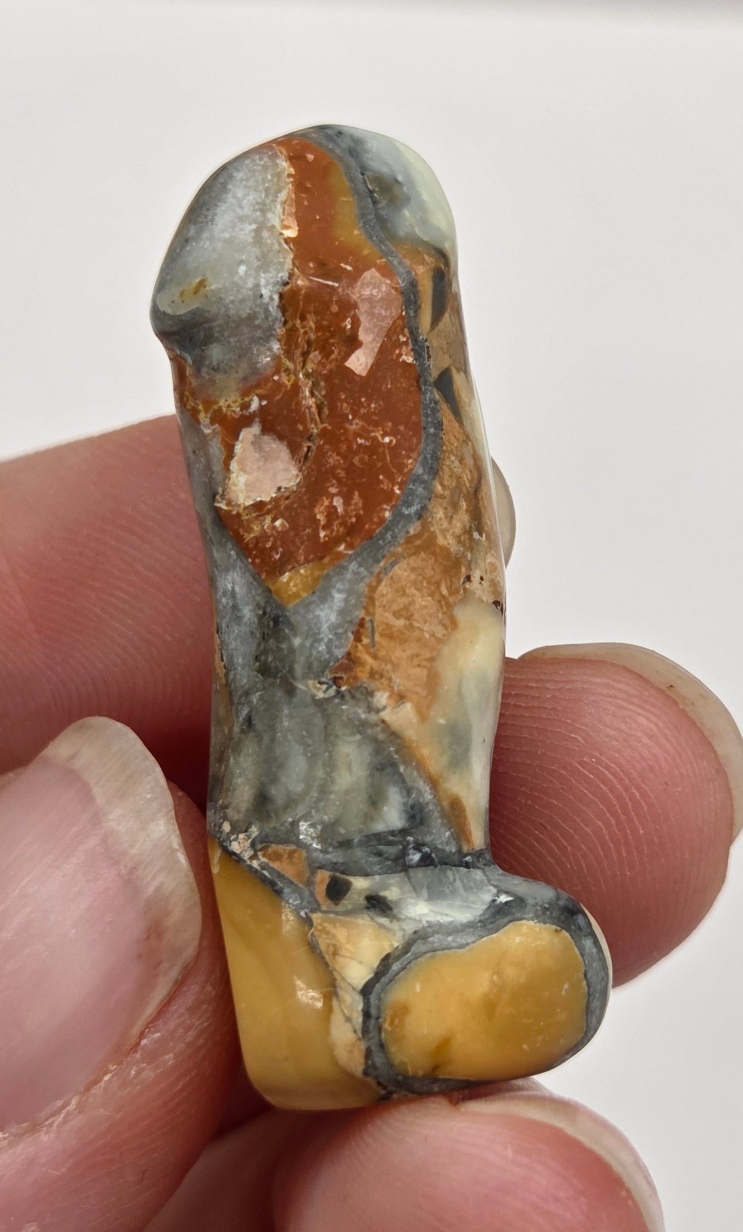 Hand holding a male anatomy crystal carving on a white background