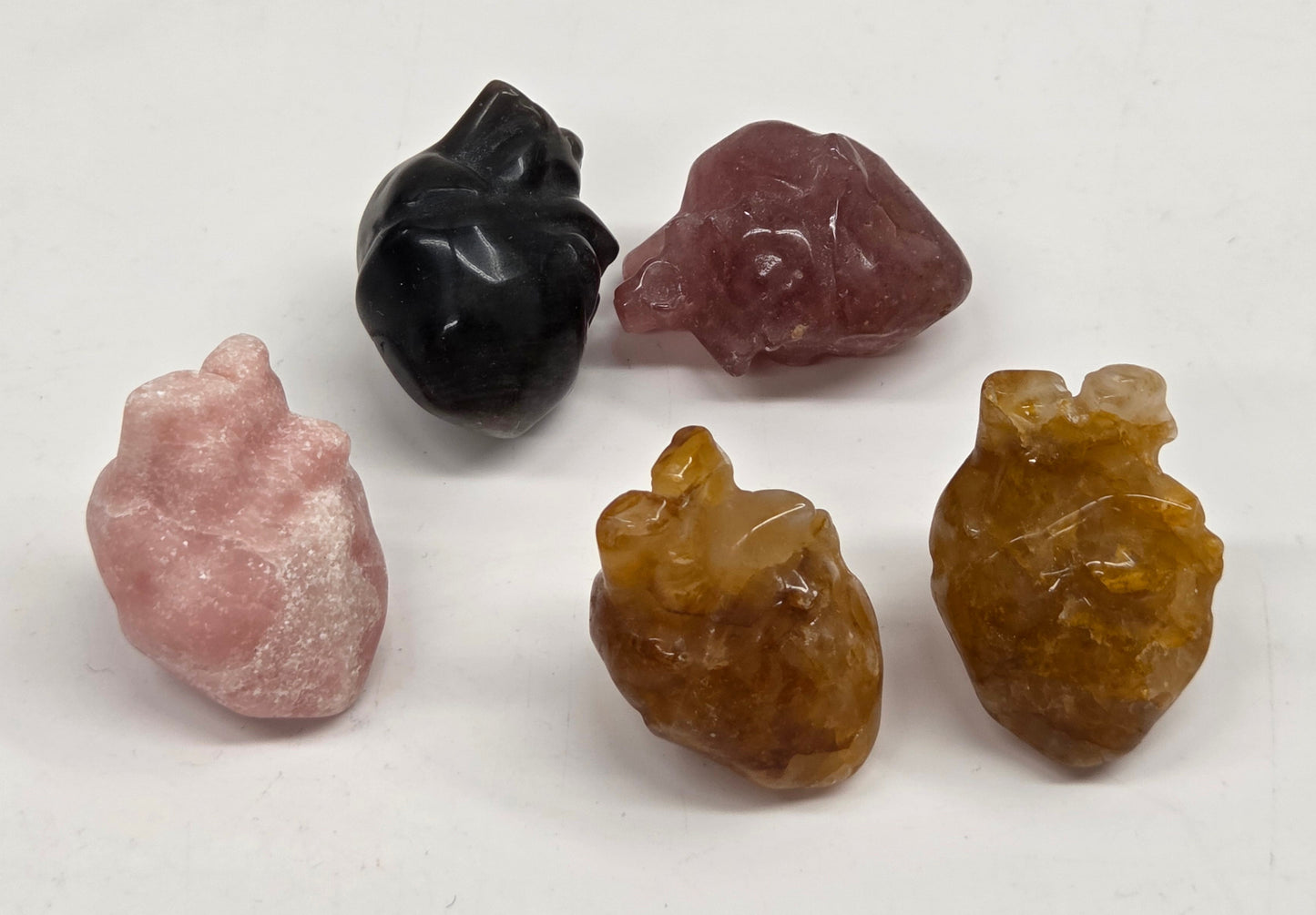 Collection of anatomical hearts in a variety of materials and colors on a white background