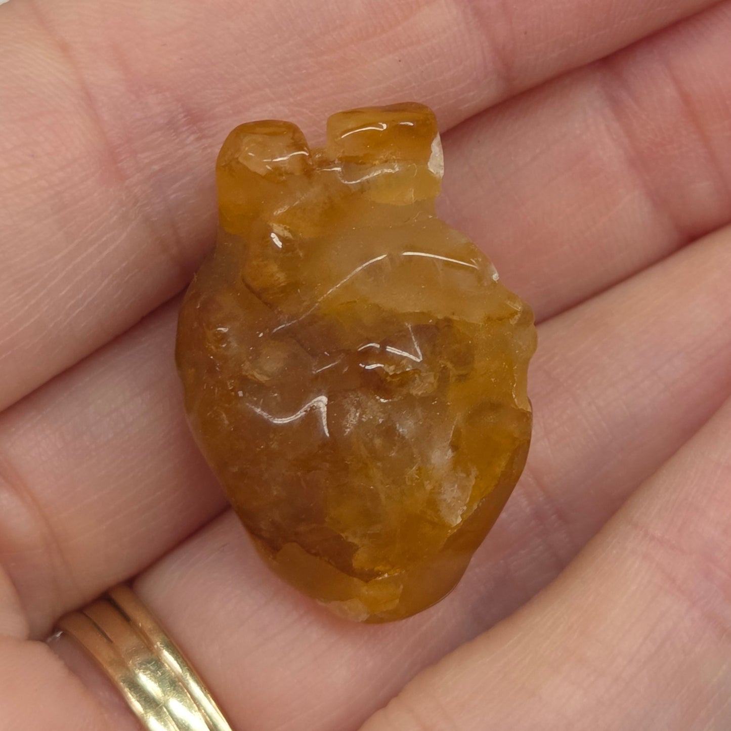 Hand holding a Golden Healer heart shaped carving on a white background