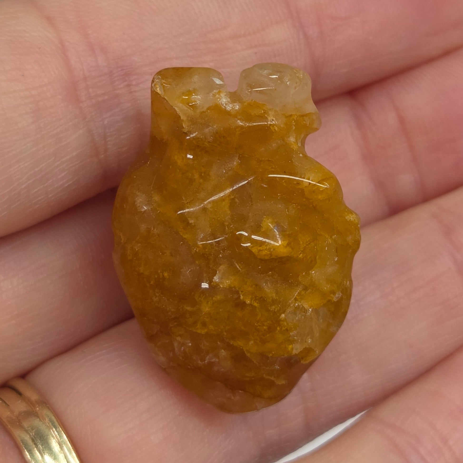 Hand holding a Golden Healer heart shaped carving on a white background