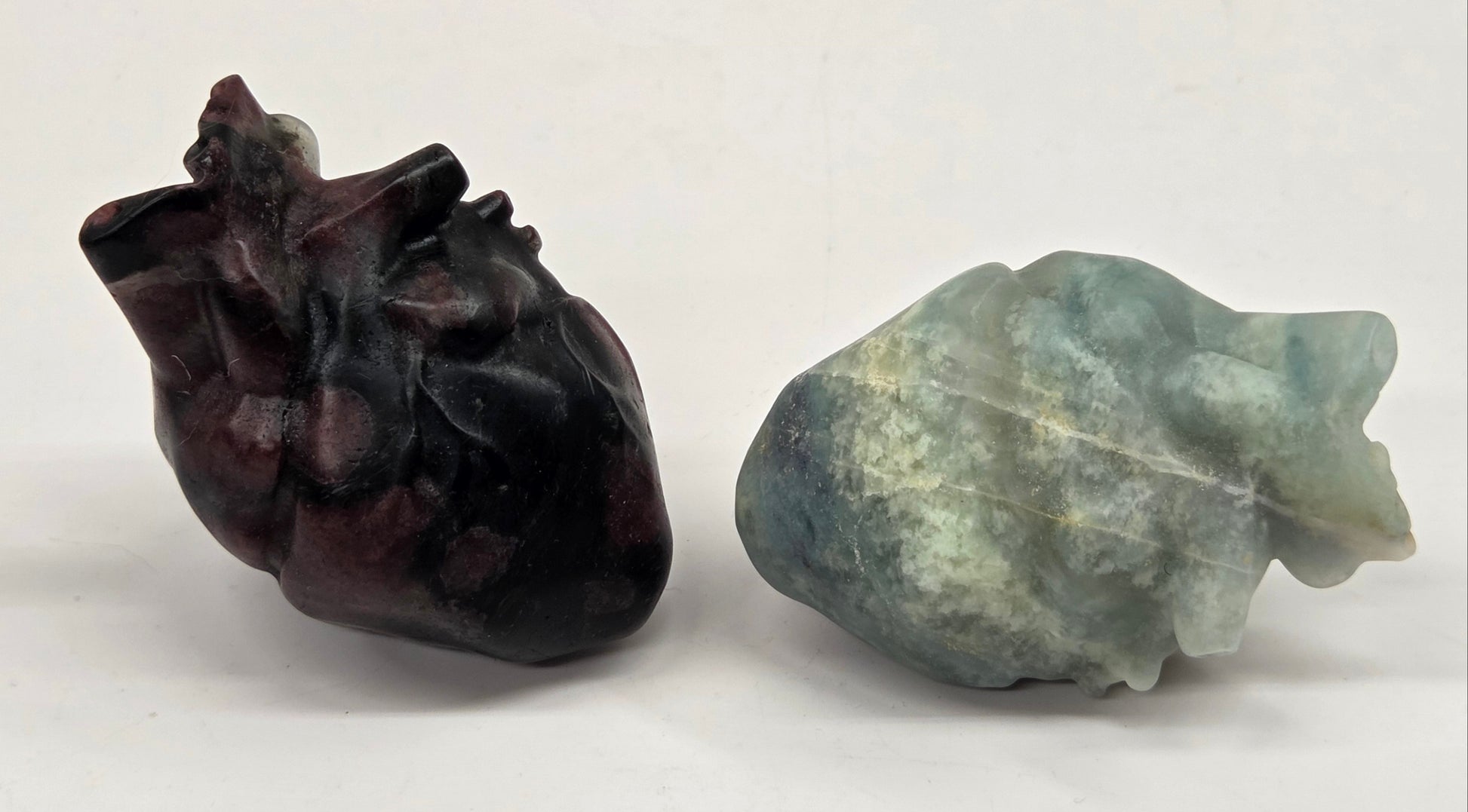 Two crystal carvings of anatomical hearts made of various materials and colors on a white background