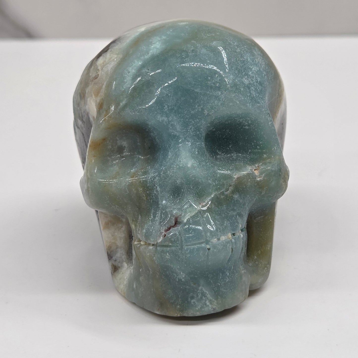 Skull carving with blue, white, black and brown coloring on a white background