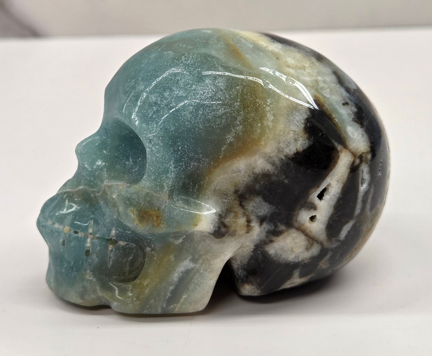 Skull carving with blue, white, black and brown coloring on a white background