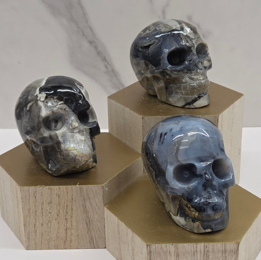 A group of skull-shaped sculptures made of volcano agate, displayed on wooden block