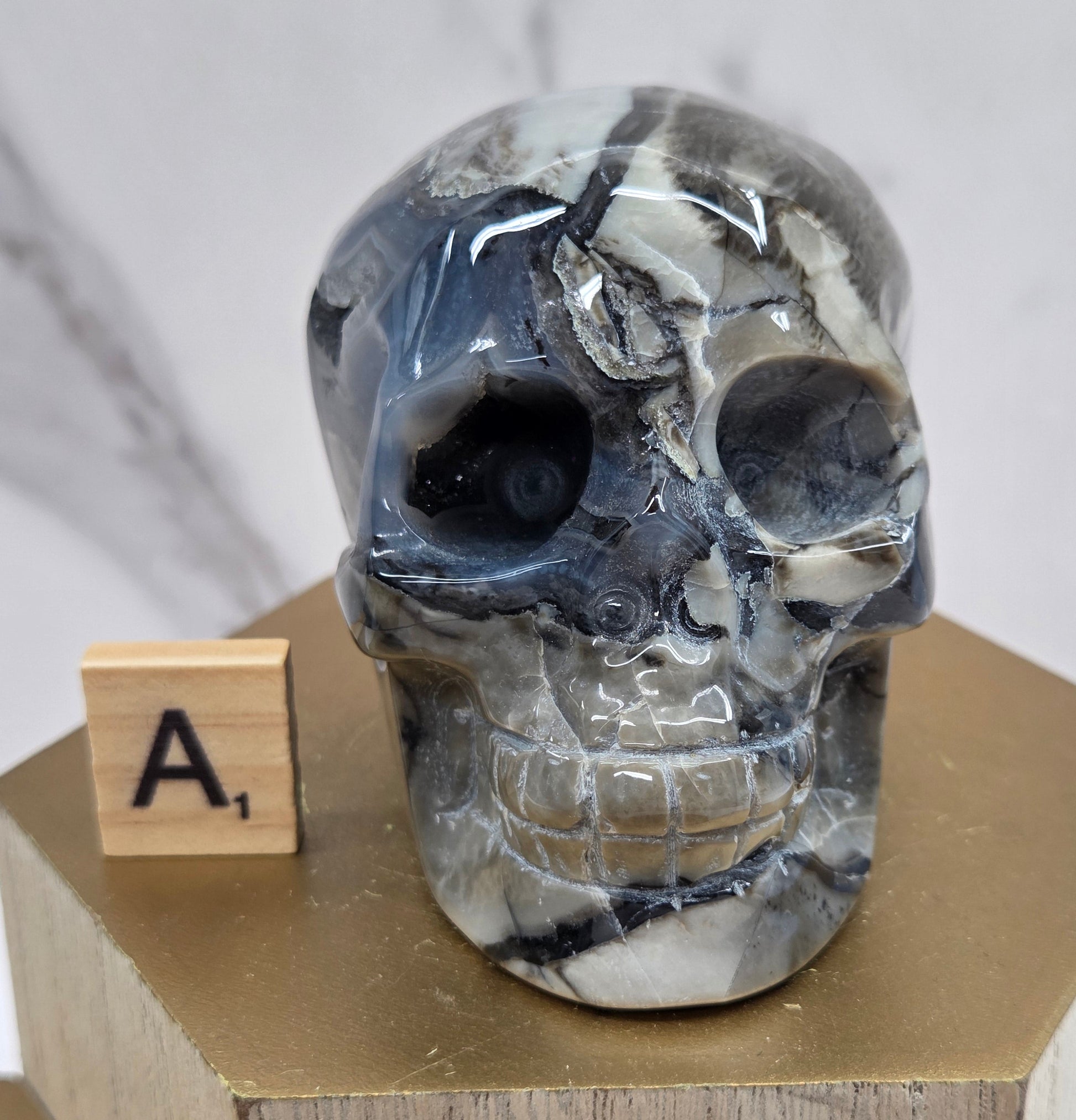 A skull-shaped sculpture made of volcano agate, displayed on wooden block