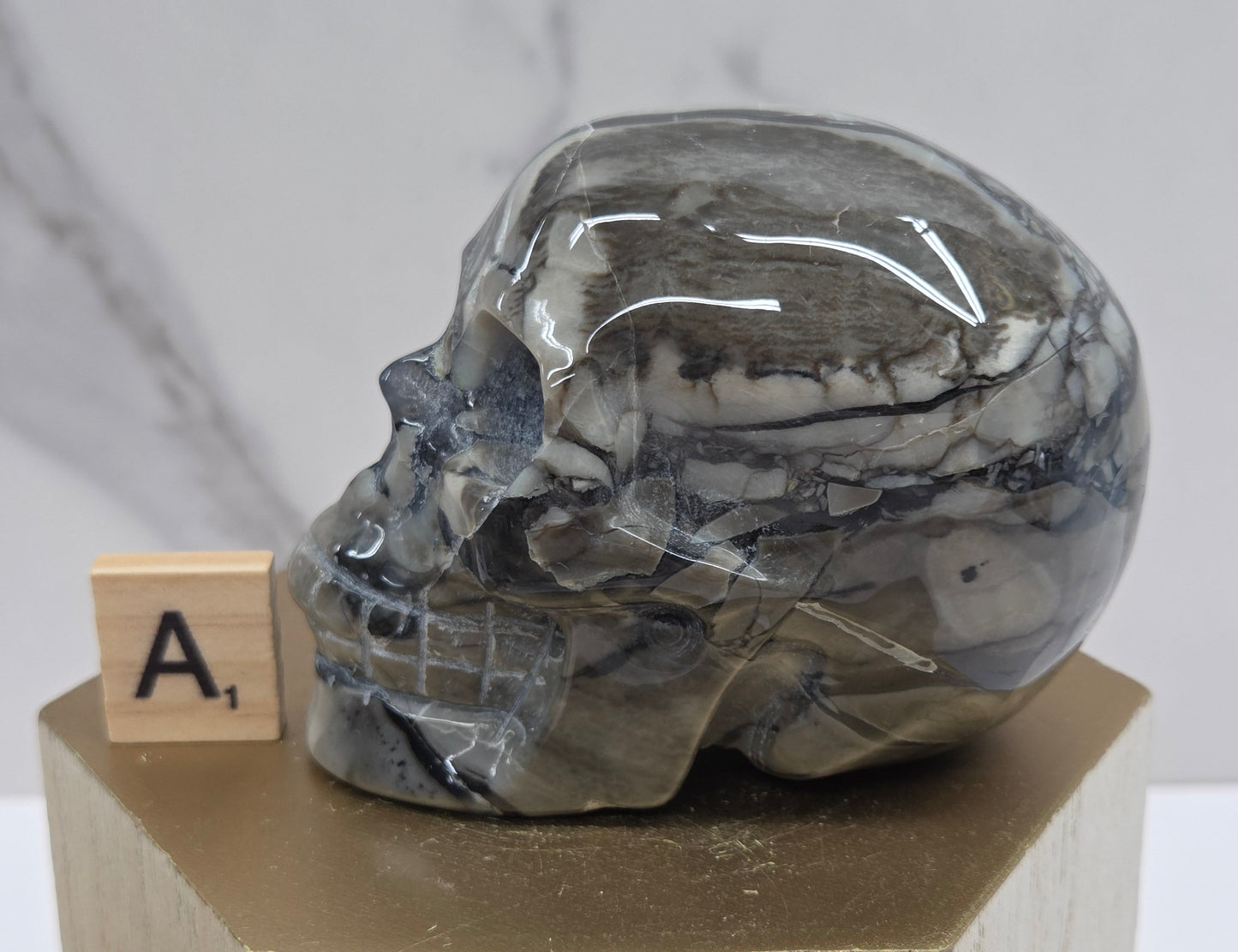 A skull-shaped sculpture made of volcano agate, displayed on wooden block