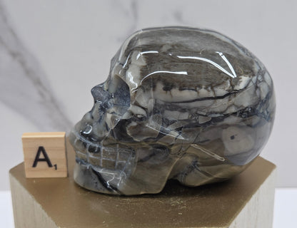 A skull-shaped sculpture made of volcano agate, displayed on wooden block