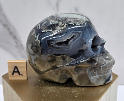 A skull-shaped sculpture made of volcano agate, displayed on wooden block