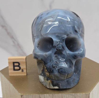 A skull-shaped sculpture made of volcano agate, displayed on wooden block