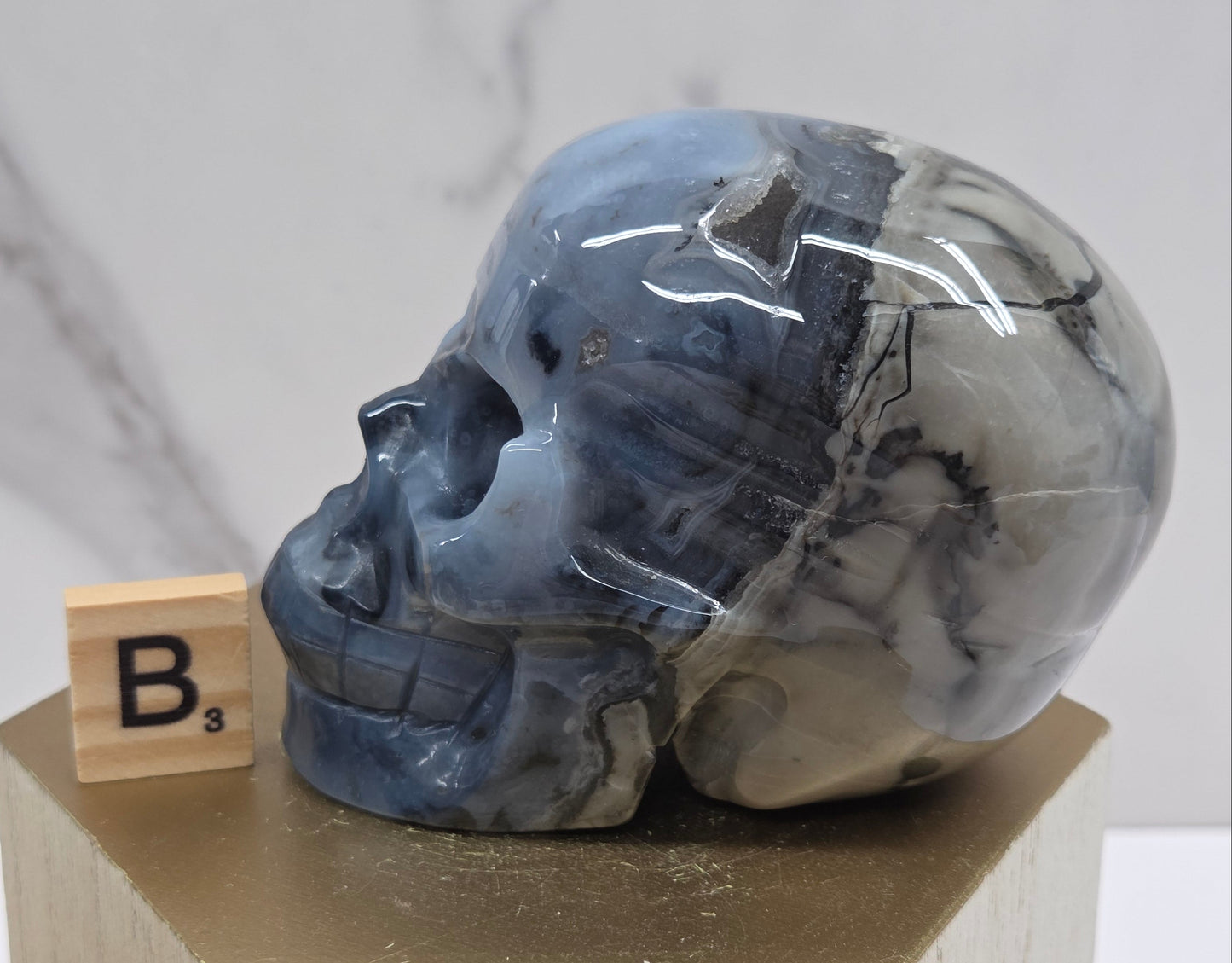 A skull-shaped sculpture made of volcano agate, displayed on wooden block