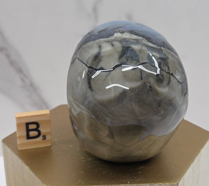 A skull-shaped sculpture made of volcano agate, displayed on wooden block