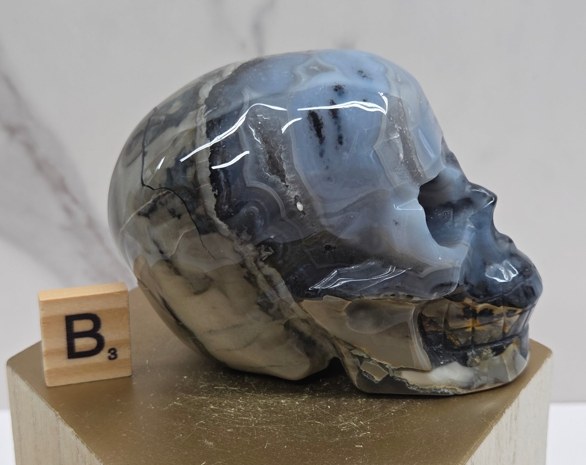 A skull-shaped sculpture made of volcano agate, displayed on wooden block