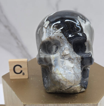 A skull-shaped sculpture made of volcano agate, displayed on wooden block