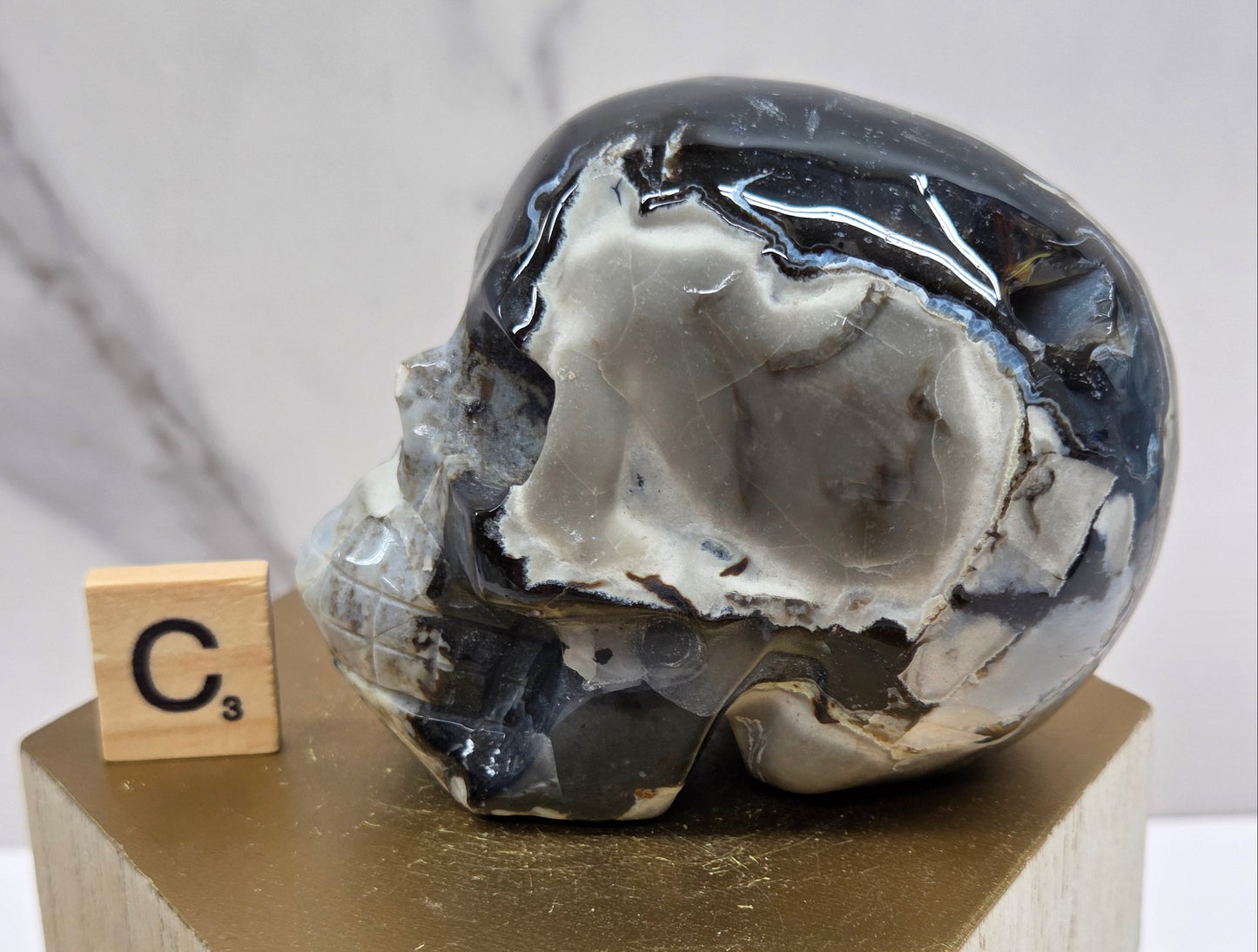 A skull-shaped sculpture made of volcano agate, displayed on wooden block