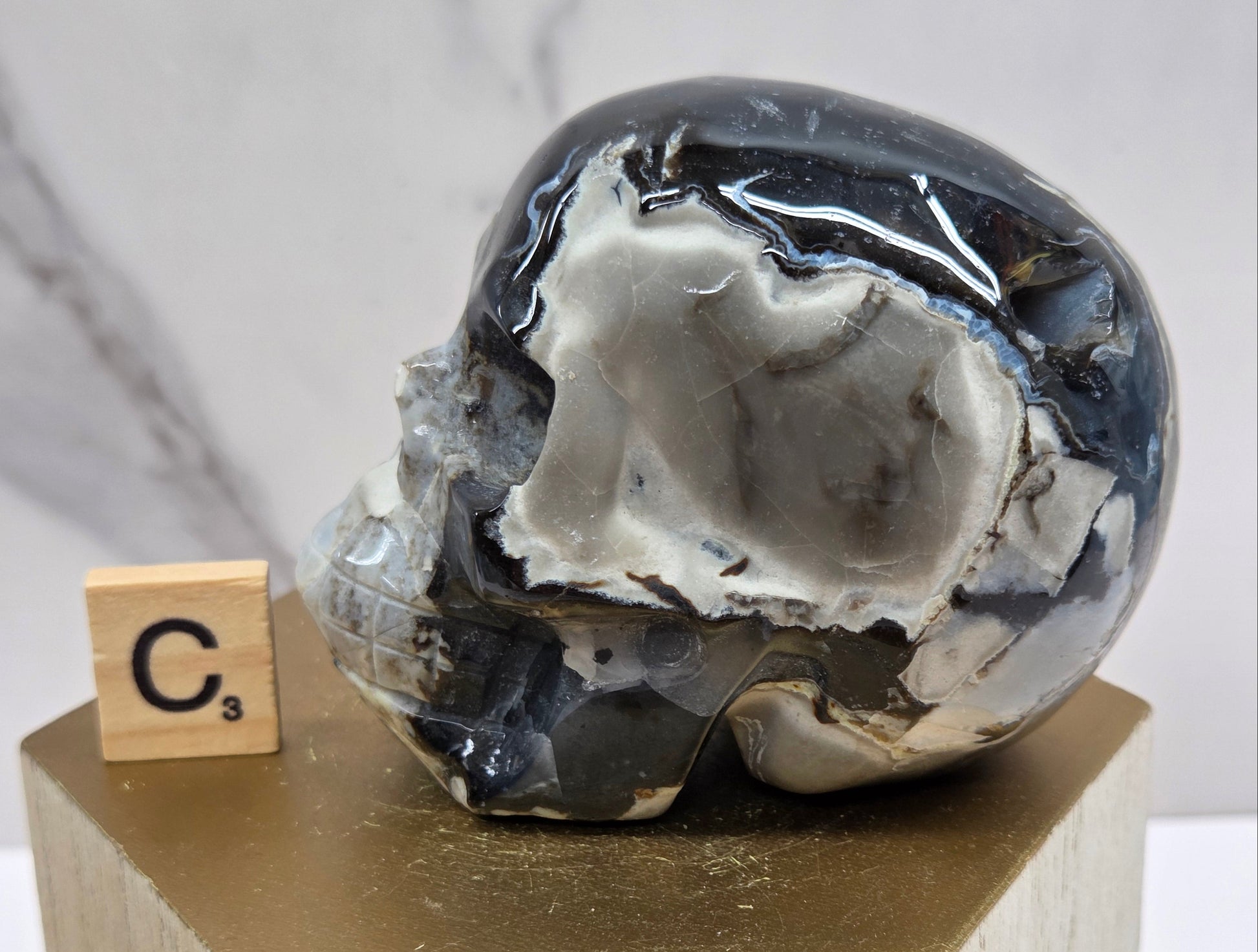 A skull-shaped sculpture made of volcano agate, displayed on wooden block