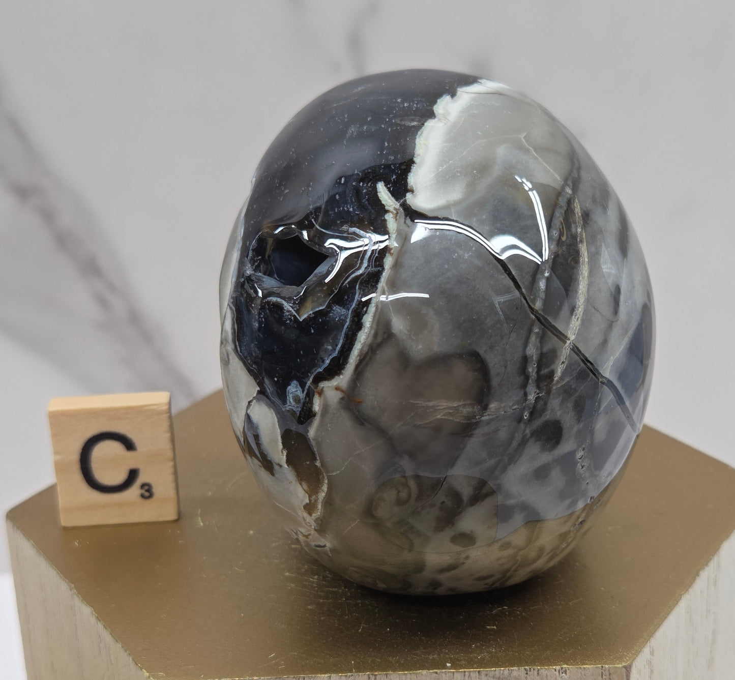 A skull-shaped sculpture made of volcano agate, displayed on wooden block