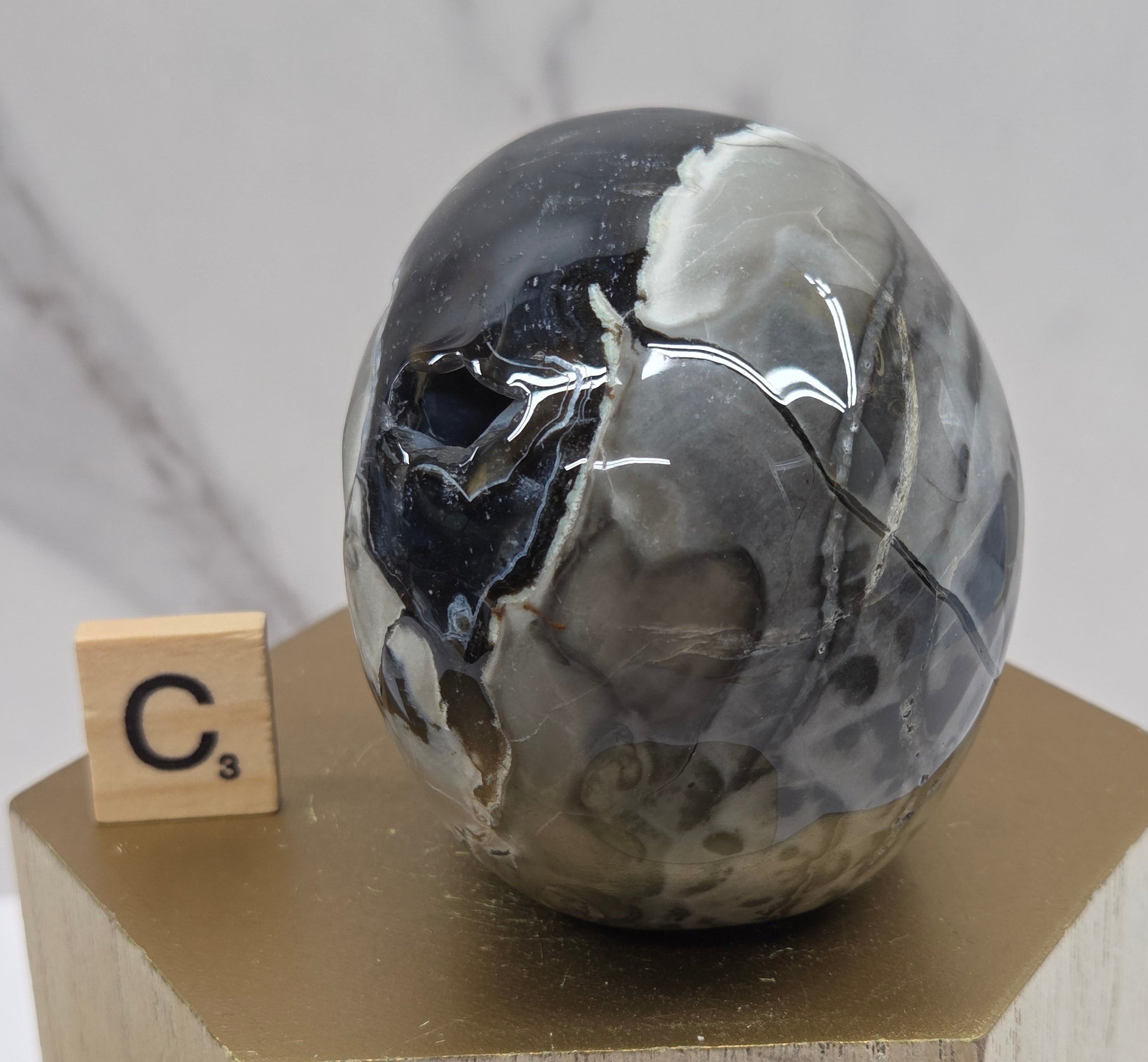 A skull-shaped sculpture made of volcano agate, displayed on wooden block