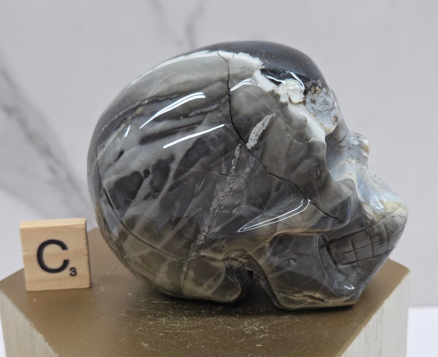 A skull-shaped sculpture made of volcano agate, displayed on wooden block