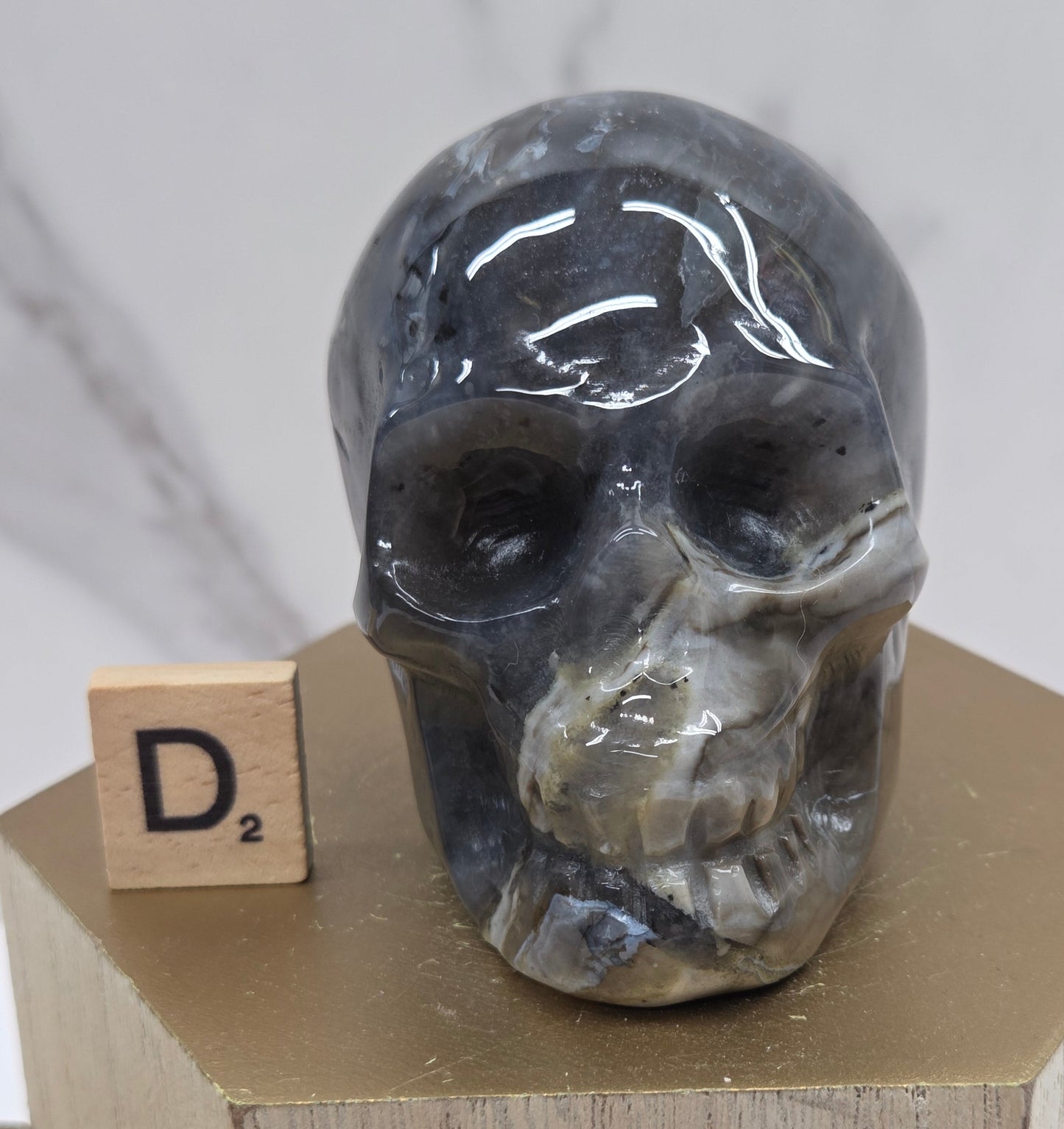 A skull-shaped sculpture made of volcano agate, displayed on wooden block