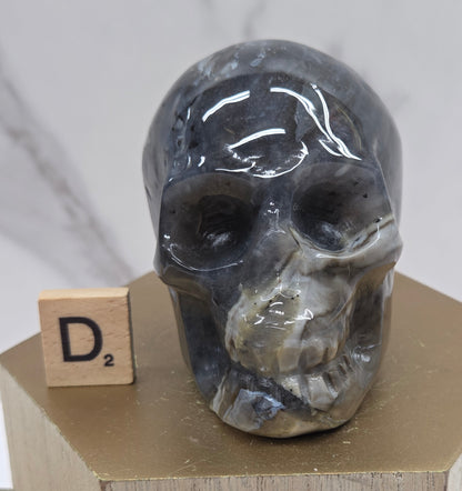 A skull-shaped sculpture made of volcano agate, displayed on wooden block