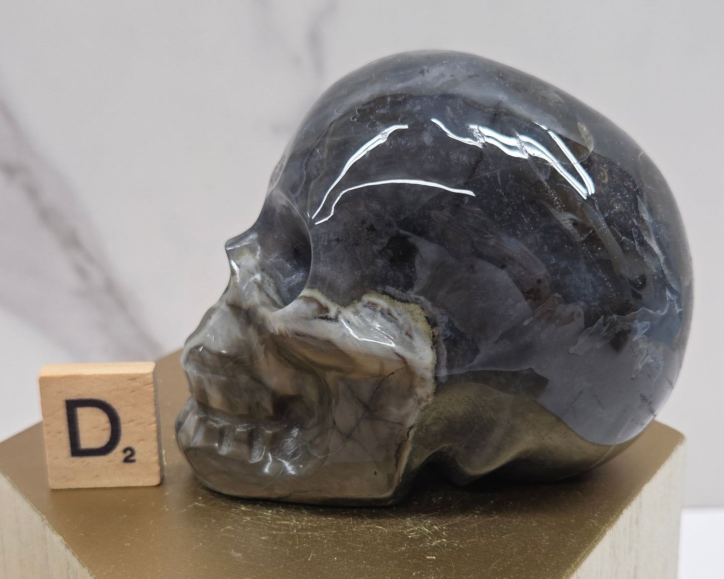 A skull-shaped sculpture made of volcano agate, displayed on wooden block