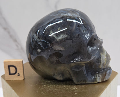 A skull-shaped sculpture made of volcano agate, displayed on wooden block