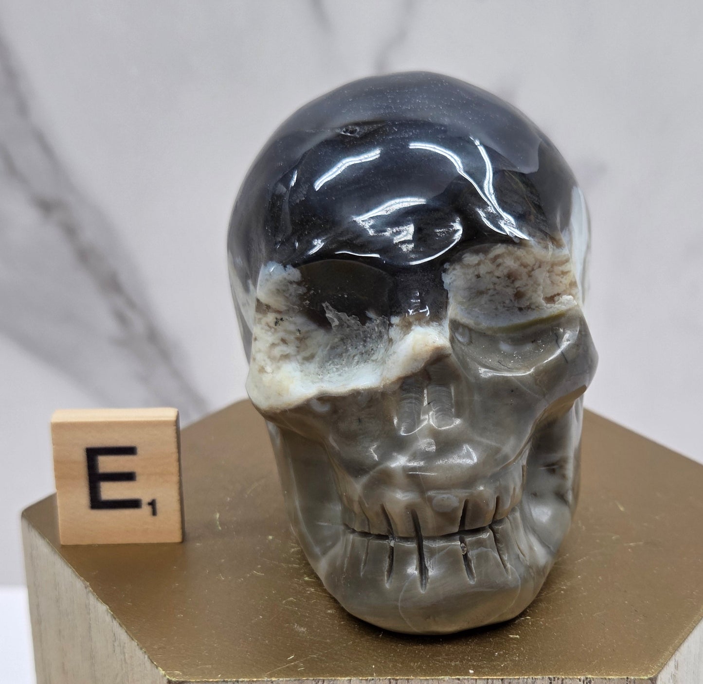 A skull-shaped sculpture made of volcano agate, displayed on wooden block
