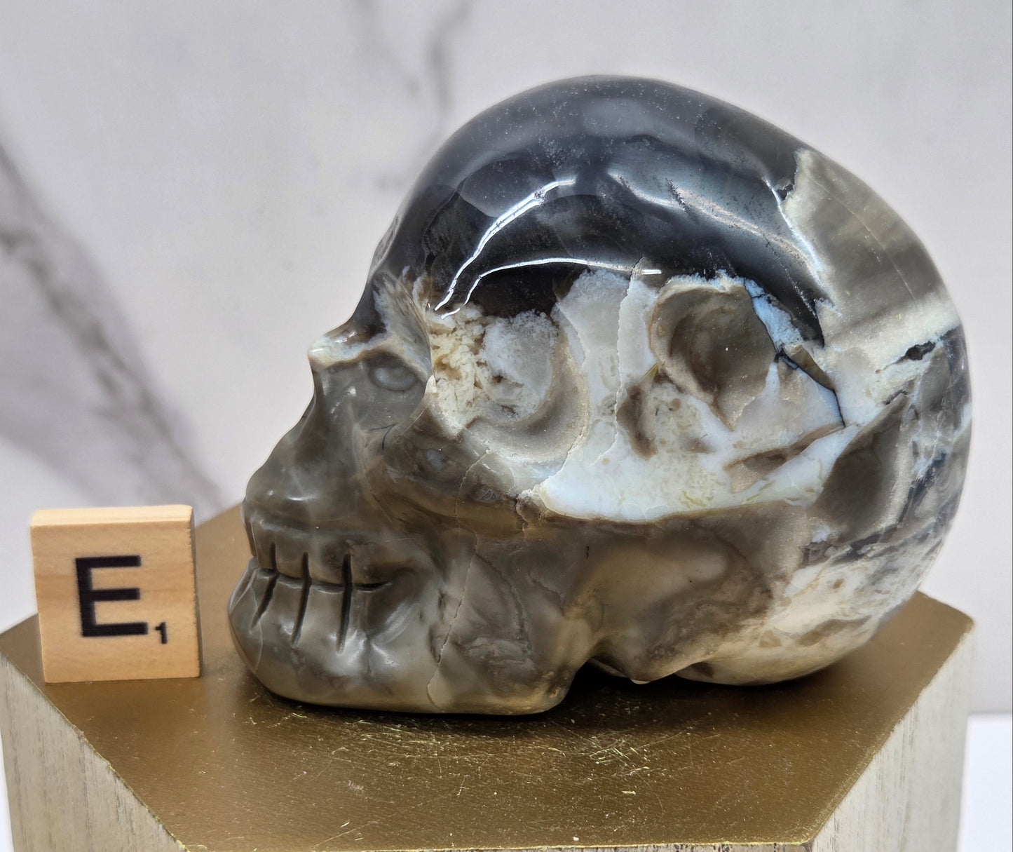 A skull-shaped sculpture made of volcano agate, displayed on wooden block