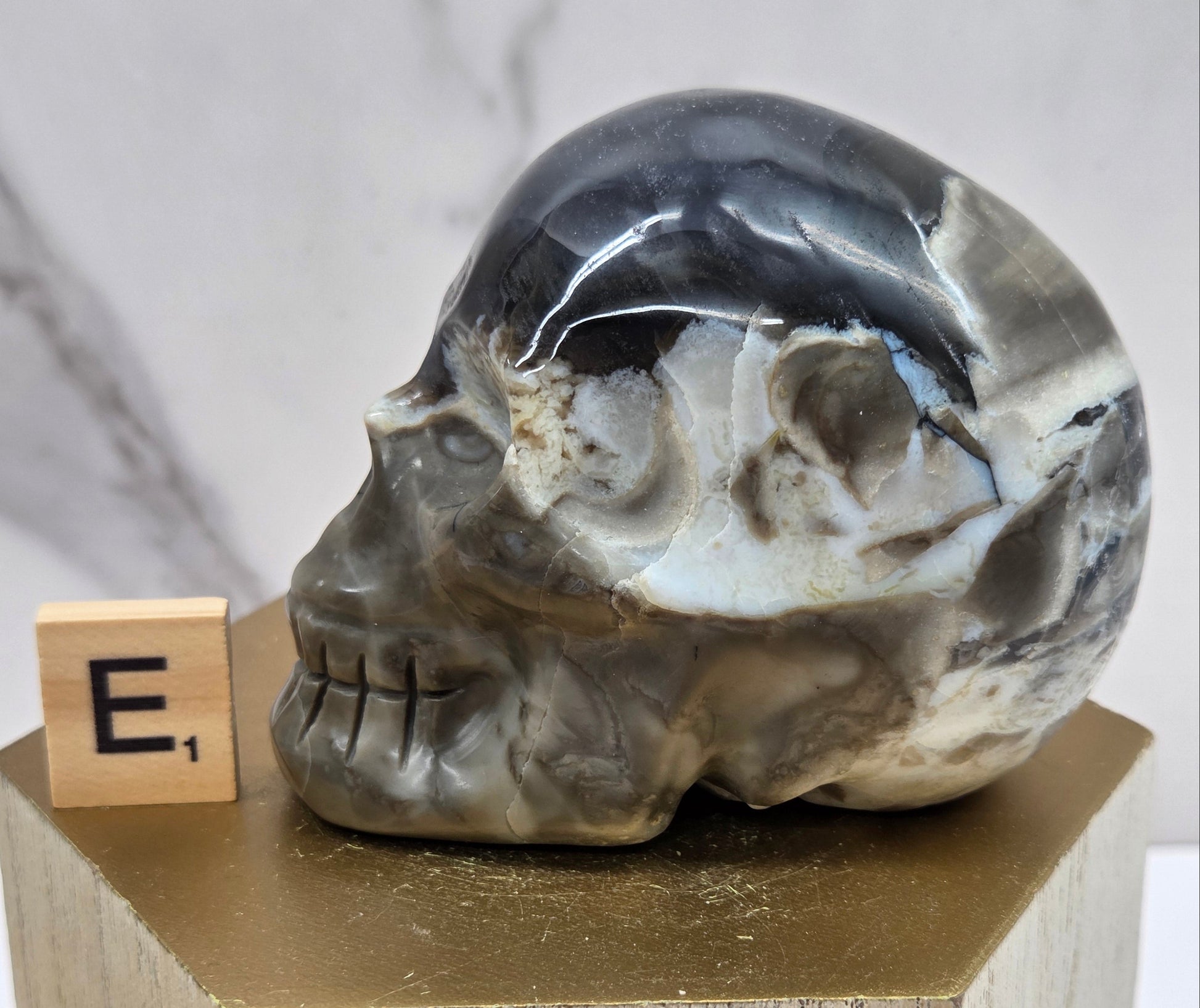 A skull-shaped sculpture made of volcano agate, displayed on wooden block