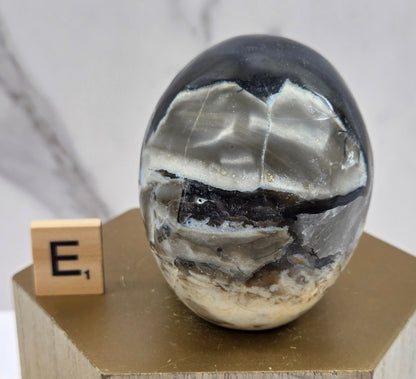 A skull-shaped sculpture made of volcano agate, displayed on wooden block