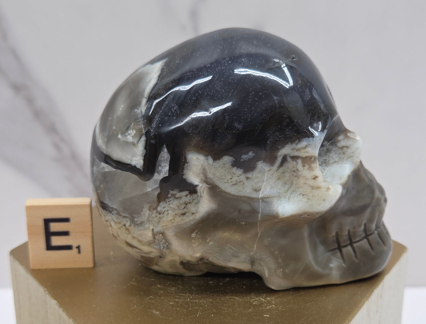 A skull-shaped sculpture made of volcano agate, displayed on wooden block