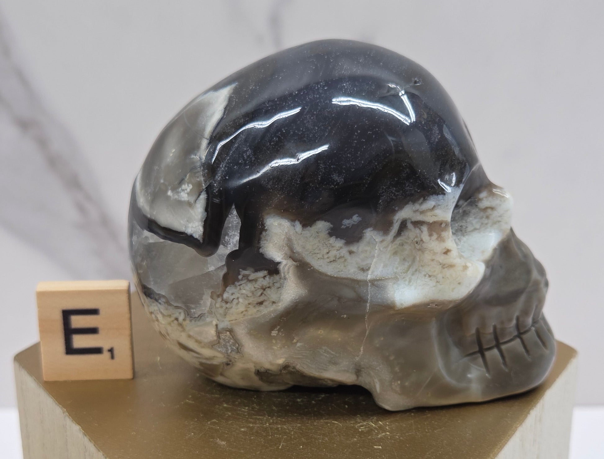 A skull-shaped sculpture made of volcano agate, displayed on wooden block