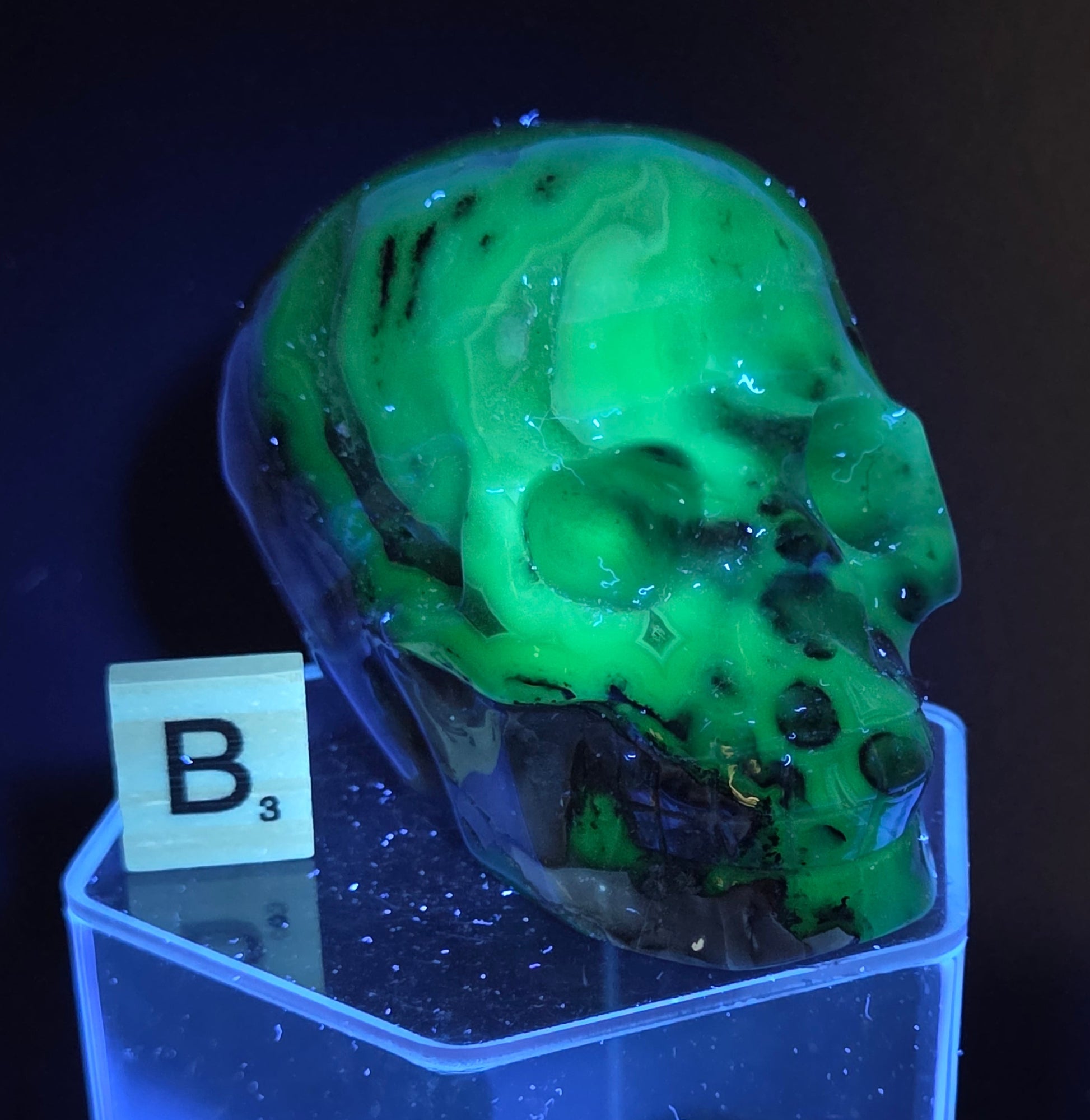 A skull-shaped sculpture made of volcano agate, under UV light