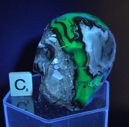 A skull-shaped sculpture made of volcano agate, under UV light