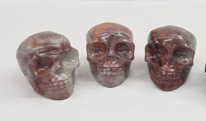 Collection of skull carvings with pink and grey coloring on a white background