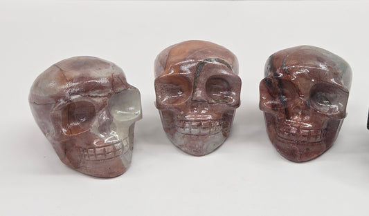 Collection of skull carvings with pink and grey coloring on a white background